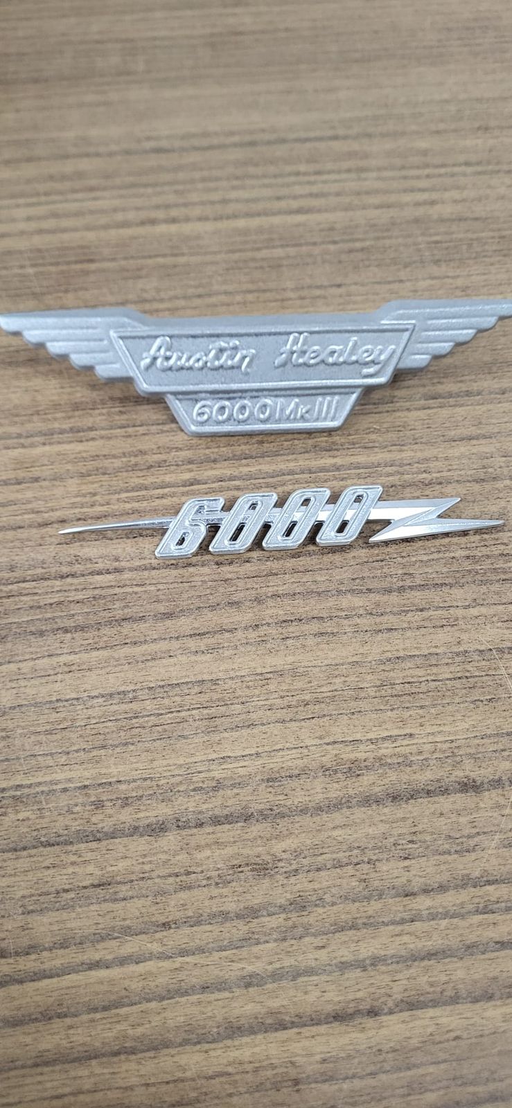 Zwei Embleme in Aluminiumguss auf Holzuntergrund