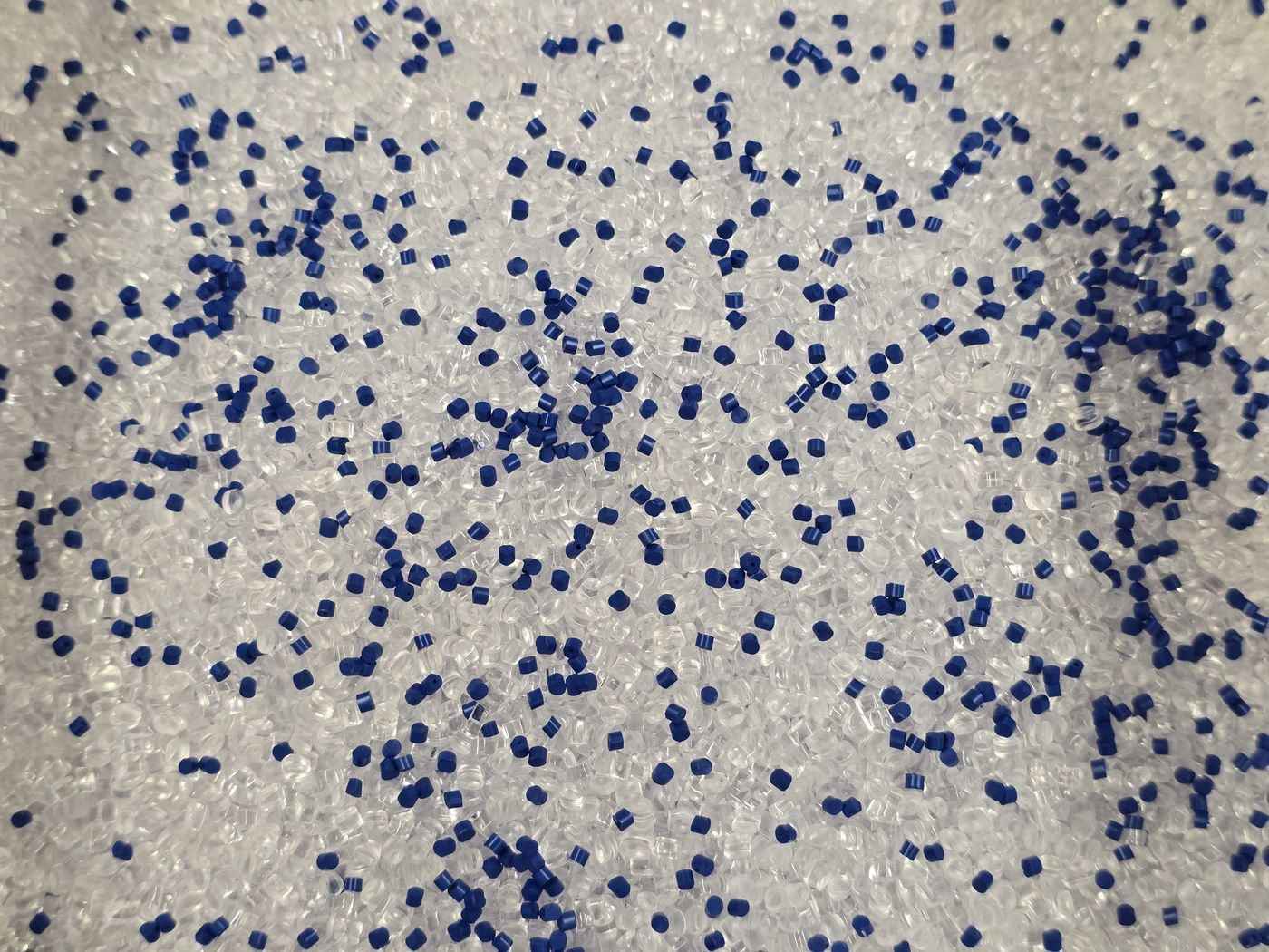 Naturfarbenes Kunststoffgranulat, vermischt mit blauem Masterbatch