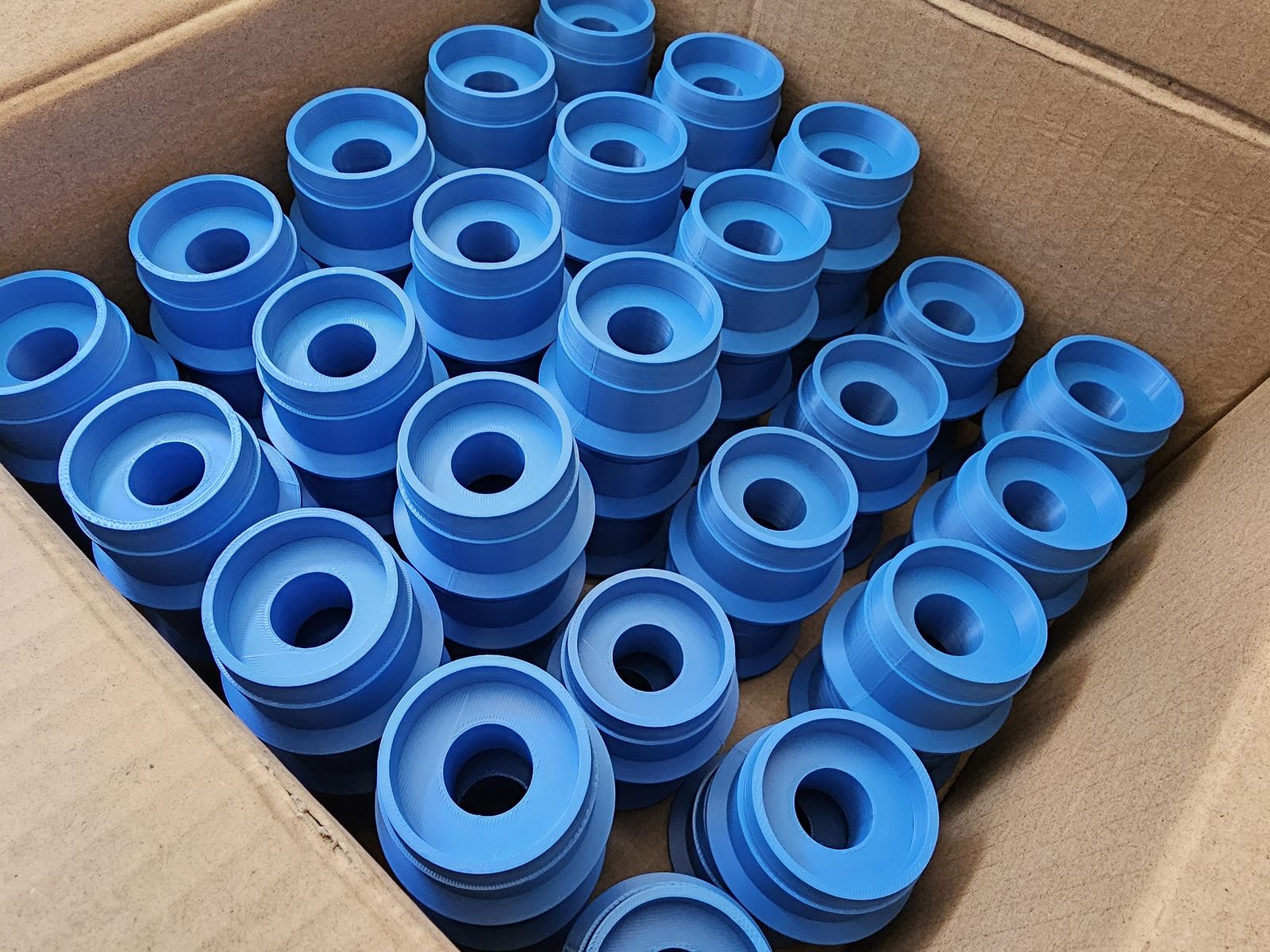 Karton voller gleicher blauer Drehteile aus dem 3D-Druck